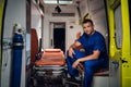 Corpsman in uniform sits in the ambulance car on the background