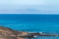 Corralejo along black rocks, blue water, view on volcanic Lobos island, Fuerteventura, Canary islands Royalty Free Stock Photo