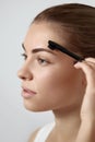 Correction and contouring eyebrows. Beautiful woman shaping brows with comb. Royalty Free Stock Photo