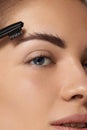 Correction and contouring eyebrows. Beautiful woman shaping brows with comb. Royalty Free Stock Photo