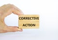 Corrective action symbol. Wooden blocks with words `Corrective action` on beautiful white background. Businessman hand. Business