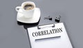 CORRELATION text on paper sheet with coffee on the black background