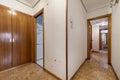 Corridor of a house with parquet checkered flooring, access to other rooms and a built-in wardrobe with ugly wooden doors Royalty Free Stock Photo