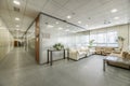 Corridor of an office building and separate offices with glass partitions, waiting areas with sofas and technical ceilings