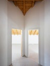 Corridor with two doors open on rooms with a sloping wooden roof