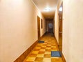 A corridor with wooden doors and a checkered floor pattern. Warmly Lit Hotel Corridor With Checkered Floor Design Royalty Free Stock Photo