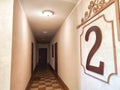 A corridor with wooden doors and a checkered floor pattern. Warmly Lit Hotel Corridor With Checkered Floor Design Royalty Free Stock Photo