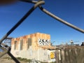 Corrugated and abandon old building with graffiti behind fencing.