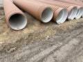 Corrugated Double-Walled Polypropylene Pipes Lined Up at a Construction Site During Daytime. Several large red Royalty Free Stock Photo