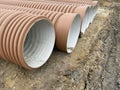 Corrugated Double-Walled Polypropylene Pipes Lined Up at a Construction Site During Daytime. Several large red Royalty Free Stock Photo