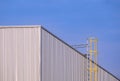 Corrugated iron Industrial Building Wall with cylinder Ladder against blue sky Background, perspective side view with copy space Royalty Free Stock Photo