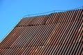 Corrugated iron roof with a lightning conductor on top. the sheet is the whole rust and forms a texture similar to Manchester fabr Royalty Free Stock Photo