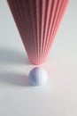 Corrugated pink paper roll and golf ball on the white desk. Royalty Free Stock Photo