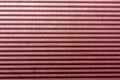 Corrugated red toned metal plate surface.