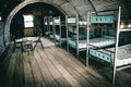 Corrugated 'Anderson' hut containing a row of bunk beds, a table, and a couple of wooden chairs. Royalty Free Stock Photo