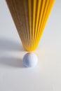 Corrugated yellow paper roll and golf ball on the white desk. Royalty Free Stock Photo