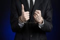 Corruption and bribery theme: businessman in a black suit with handcuffs on his hands on a dark blue background in studio isolated