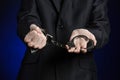 Corruption and bribery theme: businessman in a black suit with handcuffs on his hands on a dark blue background in studio isolated Royalty Free Stock Photo