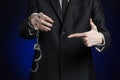 Corruption and bribery theme: businessman in a black suit with handcuffs on his hands on a dark blue background in studio isolated