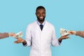 Corruption In Medicine Concept. Smiling Black Doctor Taking Money Bribe From Patient Royalty Free Stock Photo