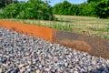 Corten steel as boundery between gravel and grass in garden Royalty Free Stock Photo