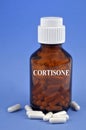 Cortisone concept with vial and capsules close-up on blue background
