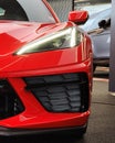 A front view of the beautiful Corvette C8 in red with headlight on at the parking lot Royalty Free Stock Photo