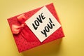 Cose-up of a gift box with a note about the words love you on a yellow background: concept of giving or declaration of love Royalty Free Stock Photo