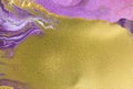 Cose up gold glitter on liquid mixed purple inks background.