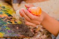 Cose up of woman hand with orange flask, over a color palette in a blurred background