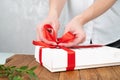Cose-up of a woman tying a ribbon on a gift. Gift wrapping concept
