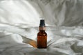 Cosmetic amber glass bottle with essential oil on white bed background with sunlights