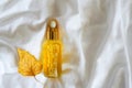 Cosmetic amber glass bottle with essential oil on white bed background with yellow falling leaf. Beauty blogging, salon treatment