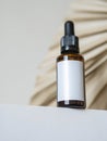 Cosmetic amber glass bottle with white lable down up on table and dry palm leaf on white background