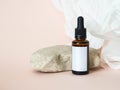 Cosmetic amber glass bottle with white lable next to the stone and white paper