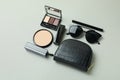 Cosmetic bag, makeup cosmetics and sunglasse on gray background