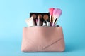 Cosmetic bag with makeup products and accessories on light blue background Royalty Free Stock Photo