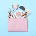 Cosmetic bag with makeup products and beauty accessories on blue background, flat lay Royalty Free Stock Photo