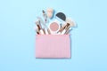 Cosmetic bag with makeup products and beauty accessories on blue background, flat lay Royalty Free Stock Photo