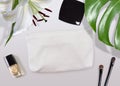 Cosmetic bag mock-up surrounded by make-up stuff and tropical plants Royalty Free Stock Photo