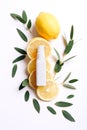 Cosmetic bottle, fresh sliced lemon with green leaves on white background, top view Royalty Free Stock Photo