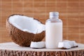 Cosmetic bottle and fresh organic coconut for skincare, natural background