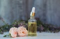 bottle with pipette and lavender and rose oil lies on a wooden table next to delicate lilac and pink fragrant flowers in Royalty Free Stock Photo