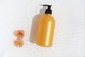 Cosmetic bottle on white background with water and flowers. Top view, closeup. Royalty Free Stock Photo