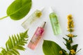 Cosmetic bottles of green, yellow, pink oil with herbal leaves on white background. Natural organic cosmetics Royalty Free Stock Photo