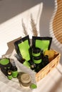 Cosmetic bottles, jars and doy packs in wicker basket with green space for brand.