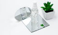 Cosmetic bottles with serum, gel, face cream on a mirror a white background with a flower. Skin cosmetics, minimalism