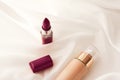 Beige tonal cream bottle make-up fluid foundation base and dark lipstick on silk background, cosmetics products as luxury beauty