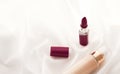 Beige tonal cream bottle make-up fluid foundation base and dark lipstick on silk background, cosmetics products as luxury beauty