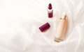 Beige tonal cream bottle make-up fluid foundation base and dark lipstick on silk background, cosmetics products as luxury beauty